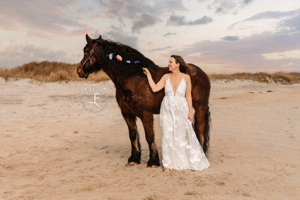 shire horse with girl in white dress on the beach