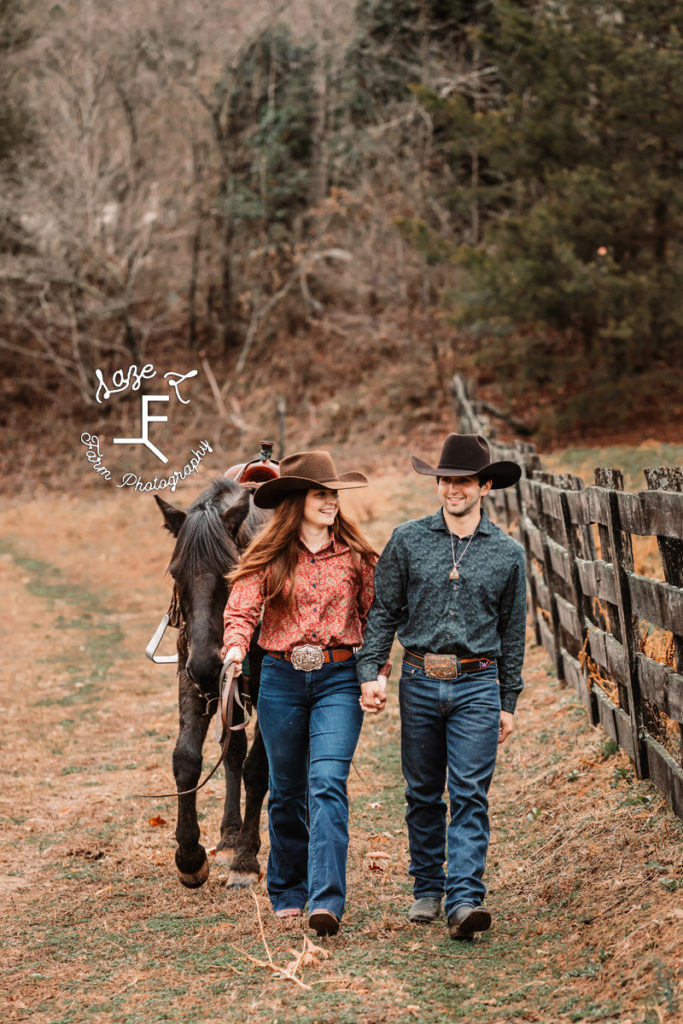 cowboy couple walking with black horse