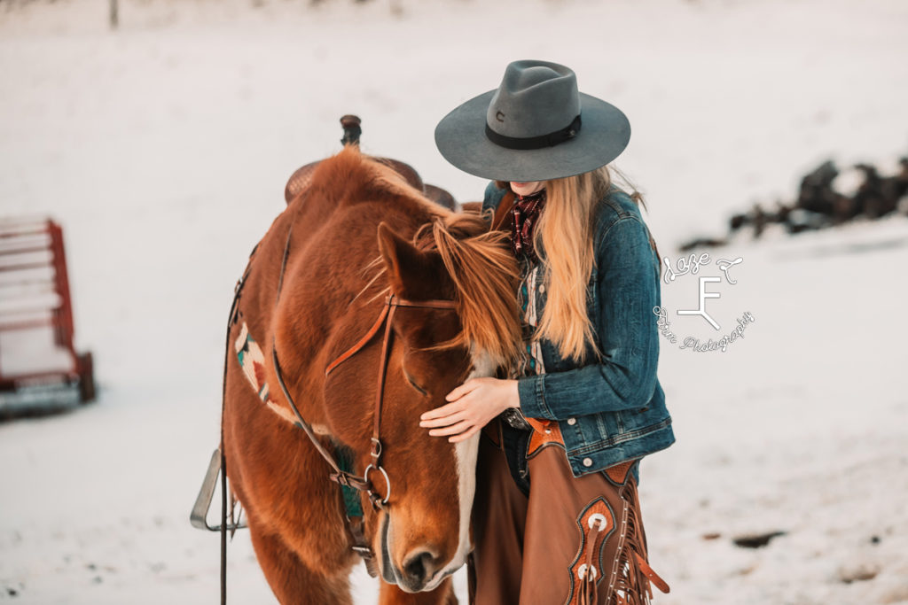 cowgirl loving on horse in the snow