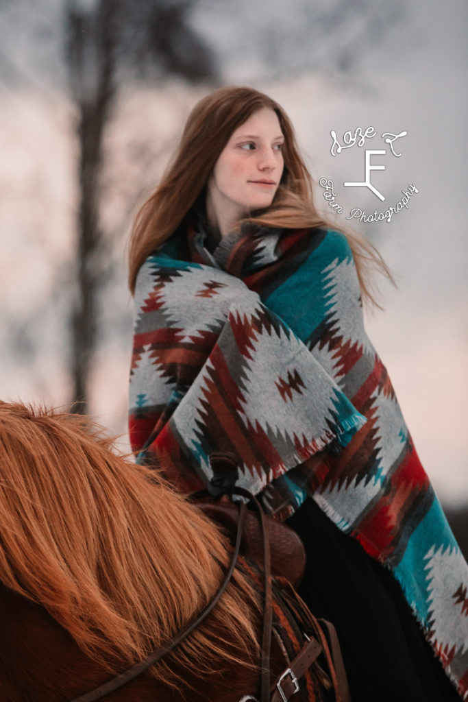 redhead girl on horseback in a blanket