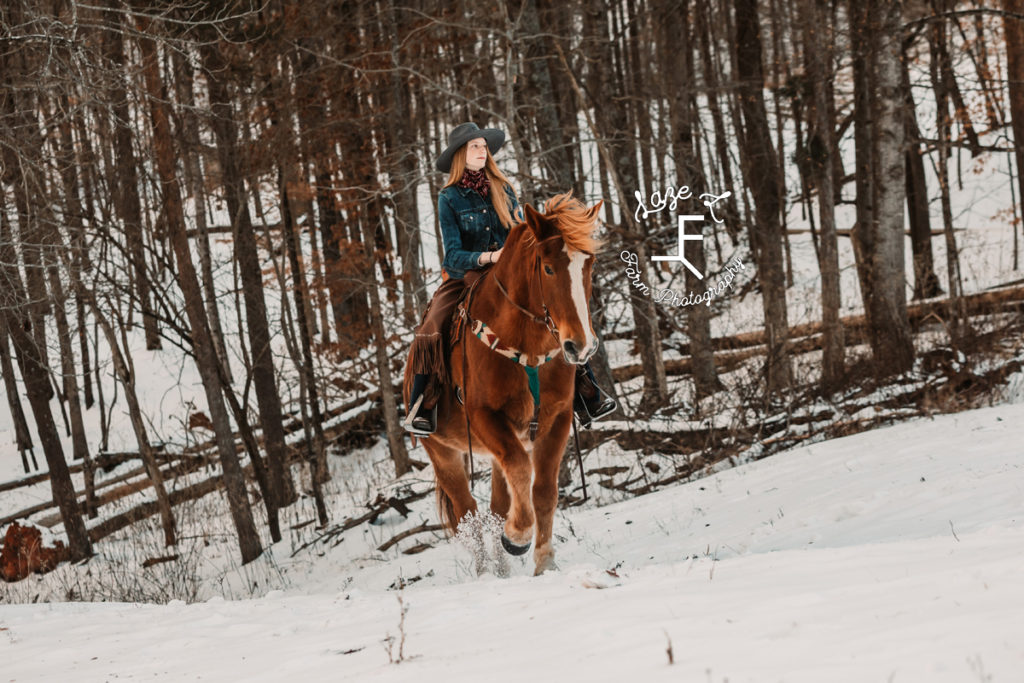 redhead cowgirl trotting in the snow
