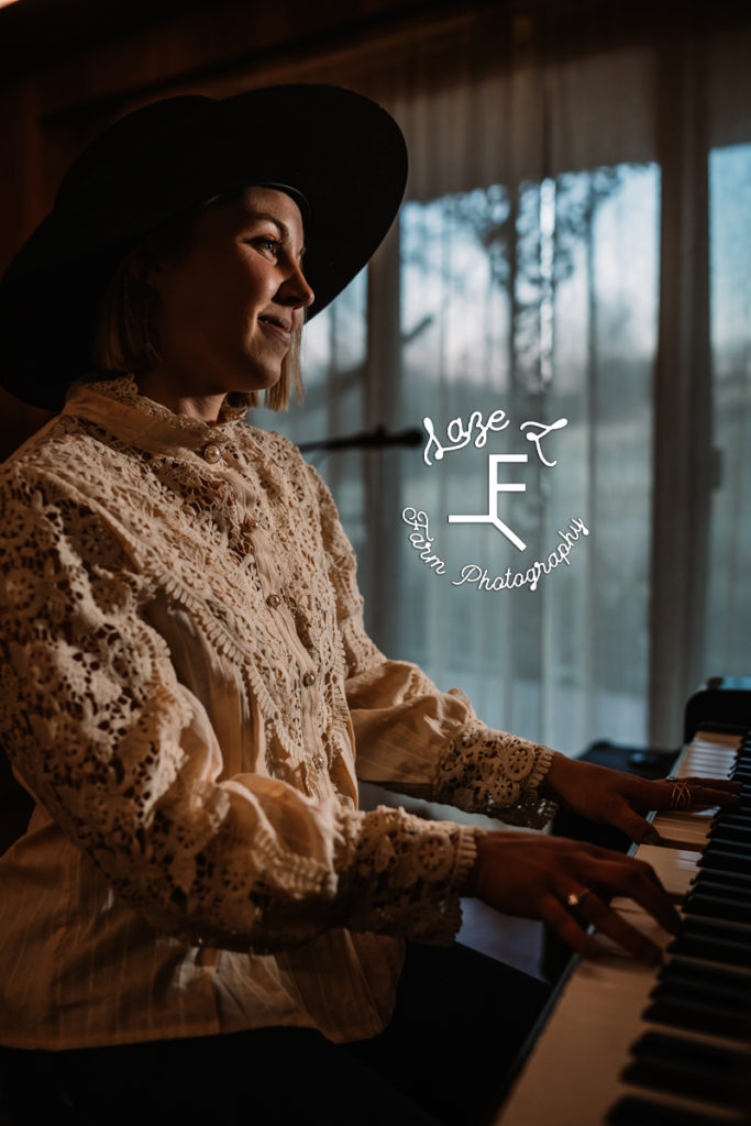 cowgirl in lace shirt playing piano