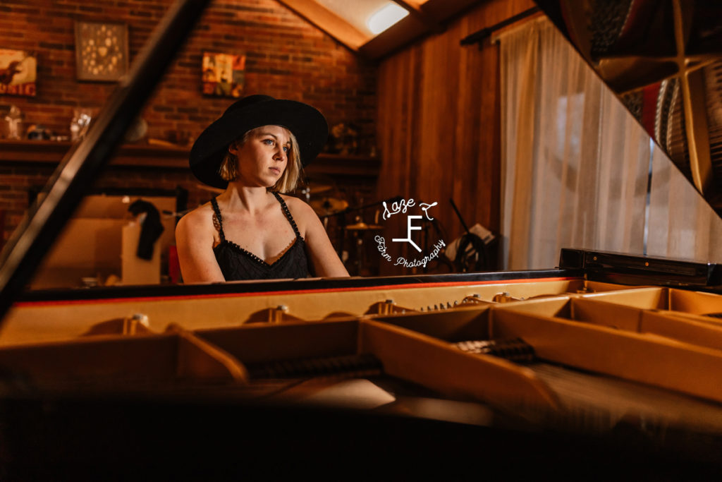 cowgirl in black dress playing grand piano