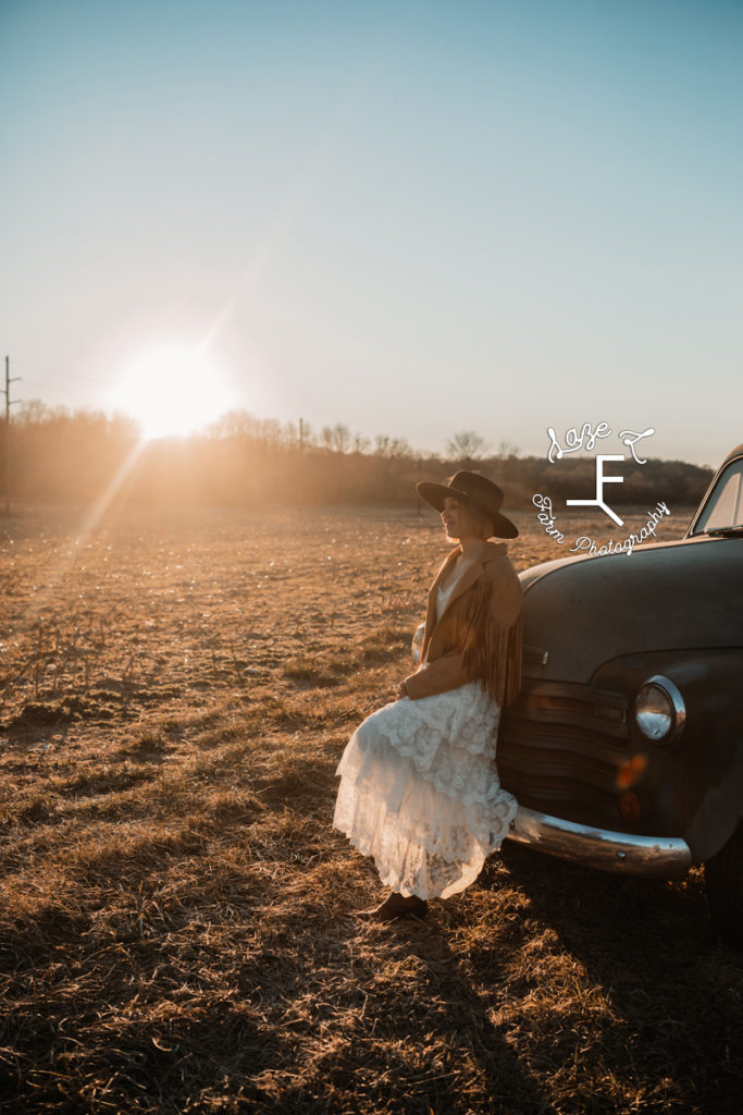 cowgirl in white dress leaning on old truck