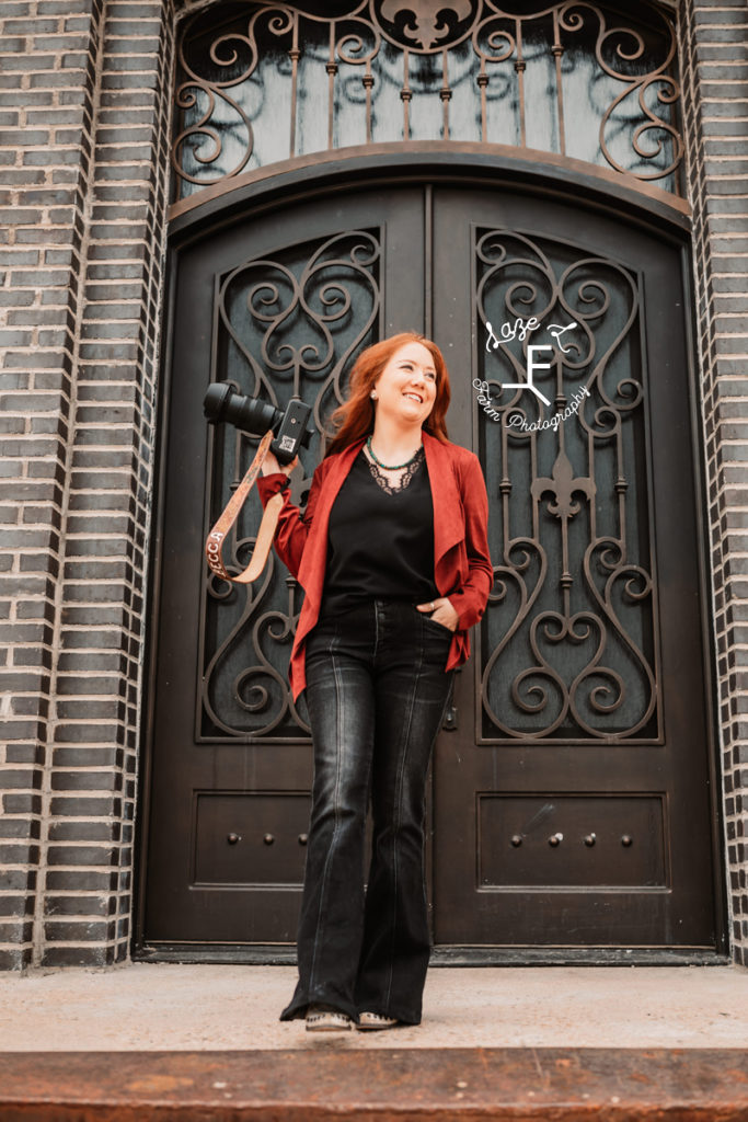 red head photographer in front of fancy doors