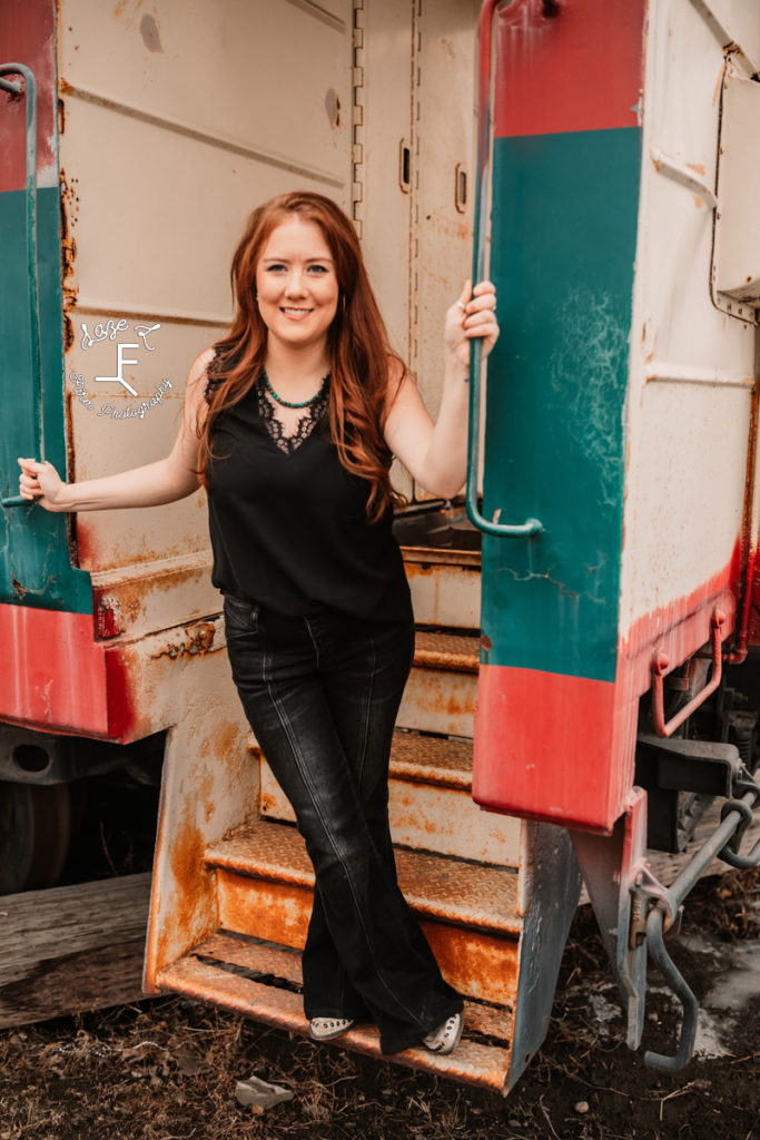 red head on a train step in black shirt