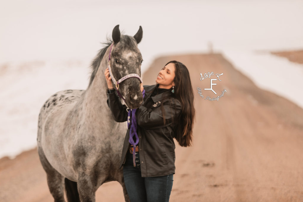 Girl with appaloosa horse on dirt road