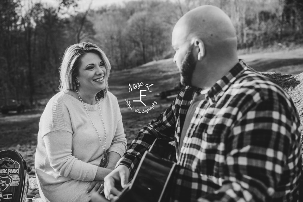guy playing guitar to fiancé in black and white