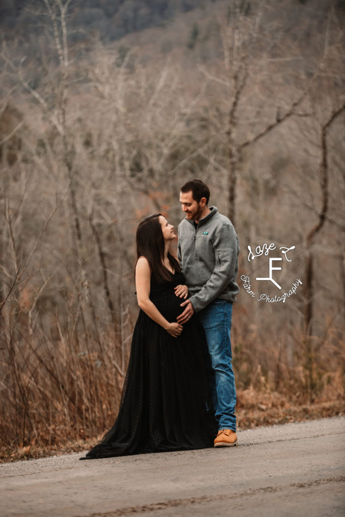 couple looking at each other holding pregnant belly
