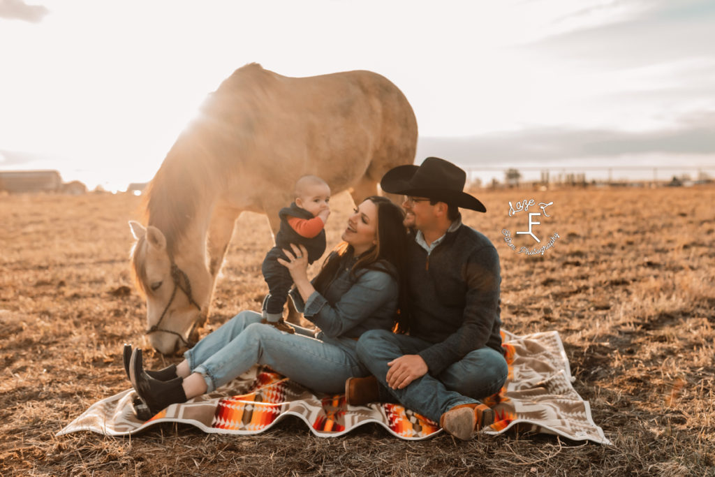 western family sitting on ground with horse grazing near them