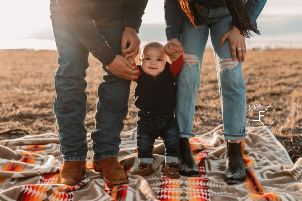 mom and dad helping baby boy stand up