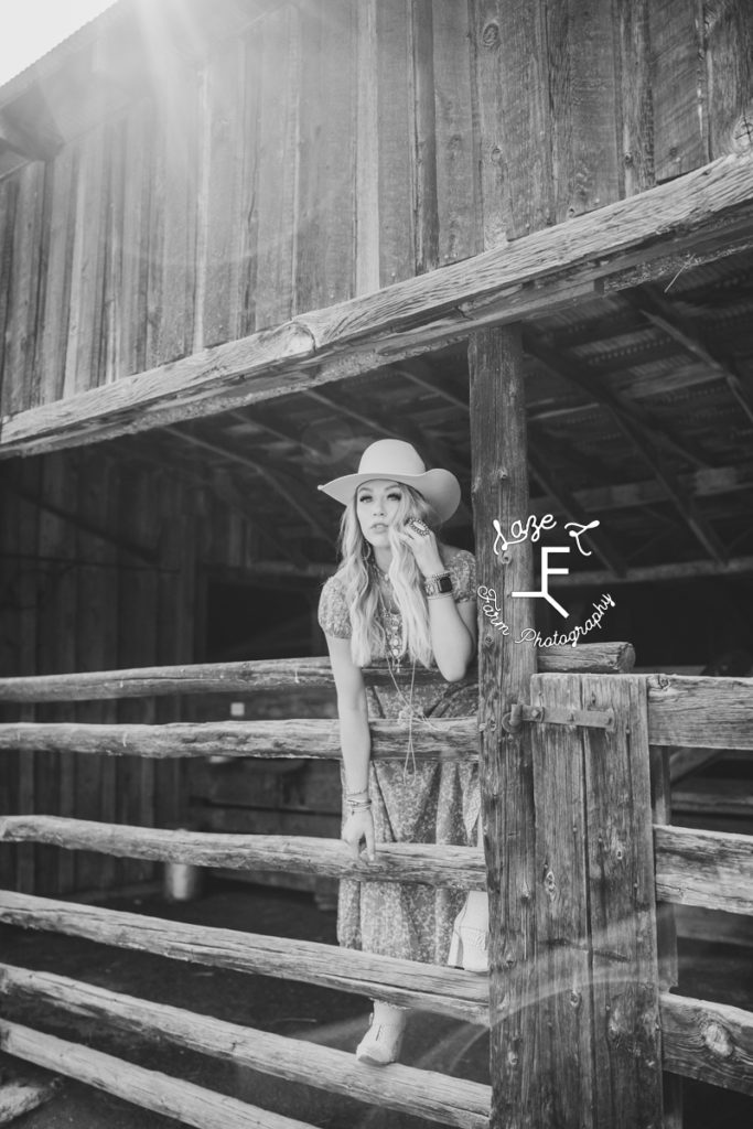 blonde cowgirl standing on wood fence