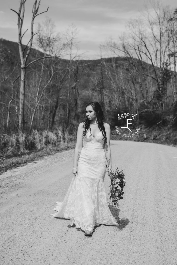 bride walking on dirt road in black an white