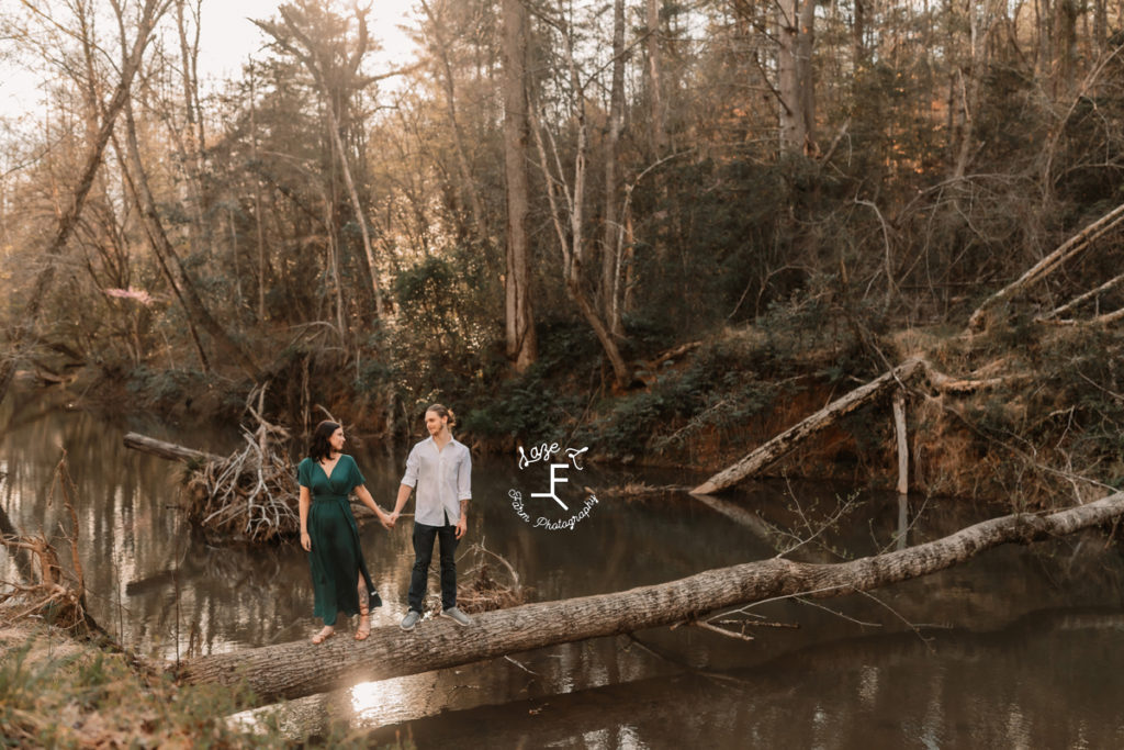 couple walking on a fallen tree across water