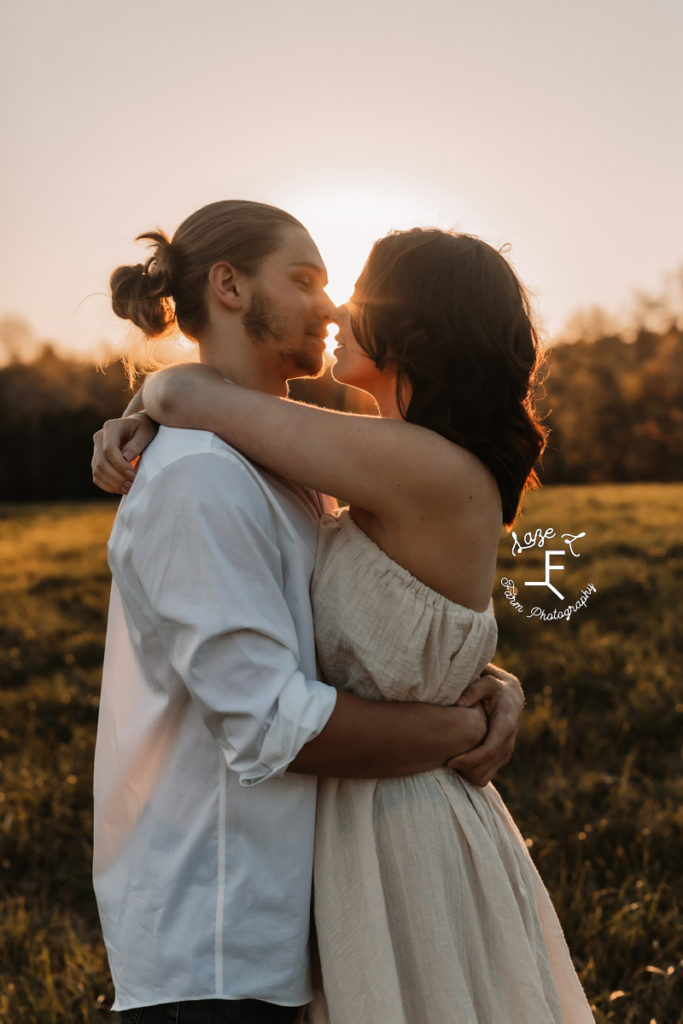 couple hugging with sun behind them