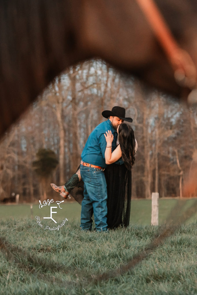 cowboy and wife sharing a kiss framed by horse head and reins