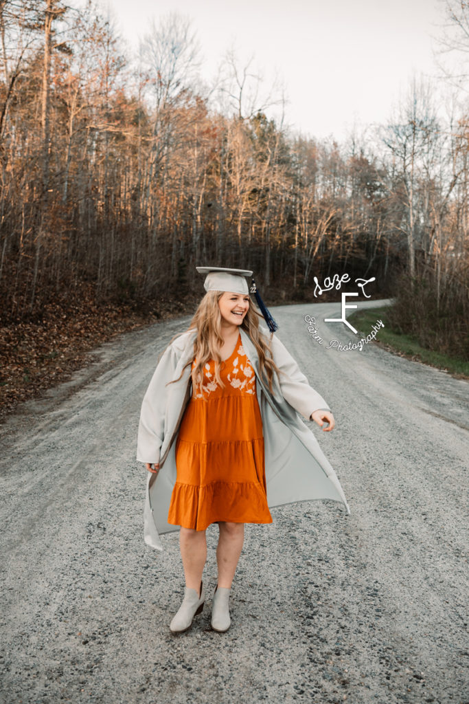 senior girl in cap and gown with orange dress