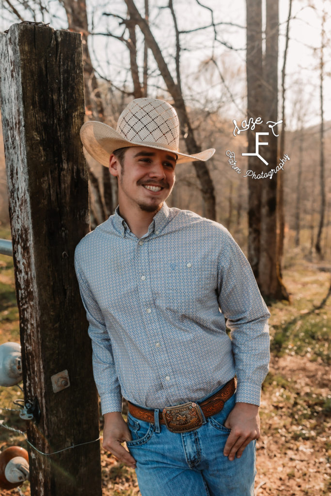 senior guy with cowboy hat against fence