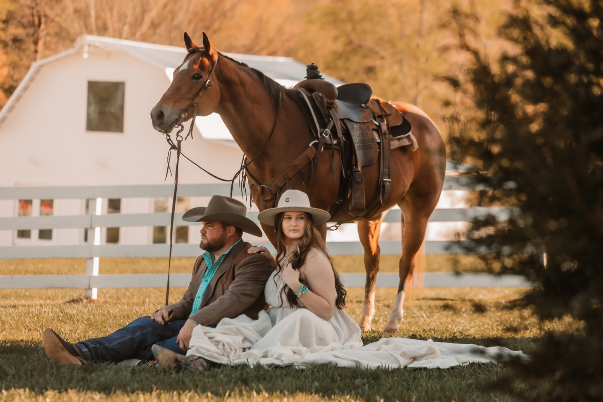 cowboy couple with horse sitting on ground