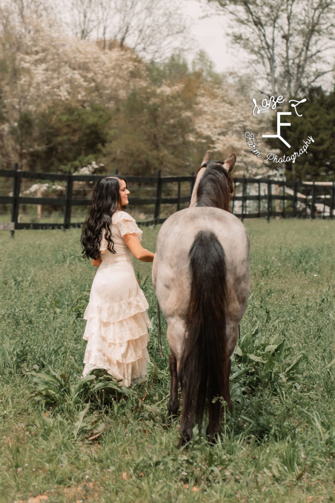 girl in vintage lace dress with horse facing away