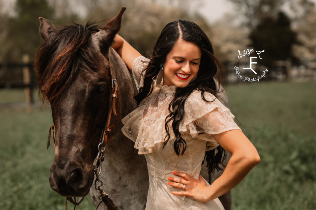girl in vintage lace dress looking down with horse