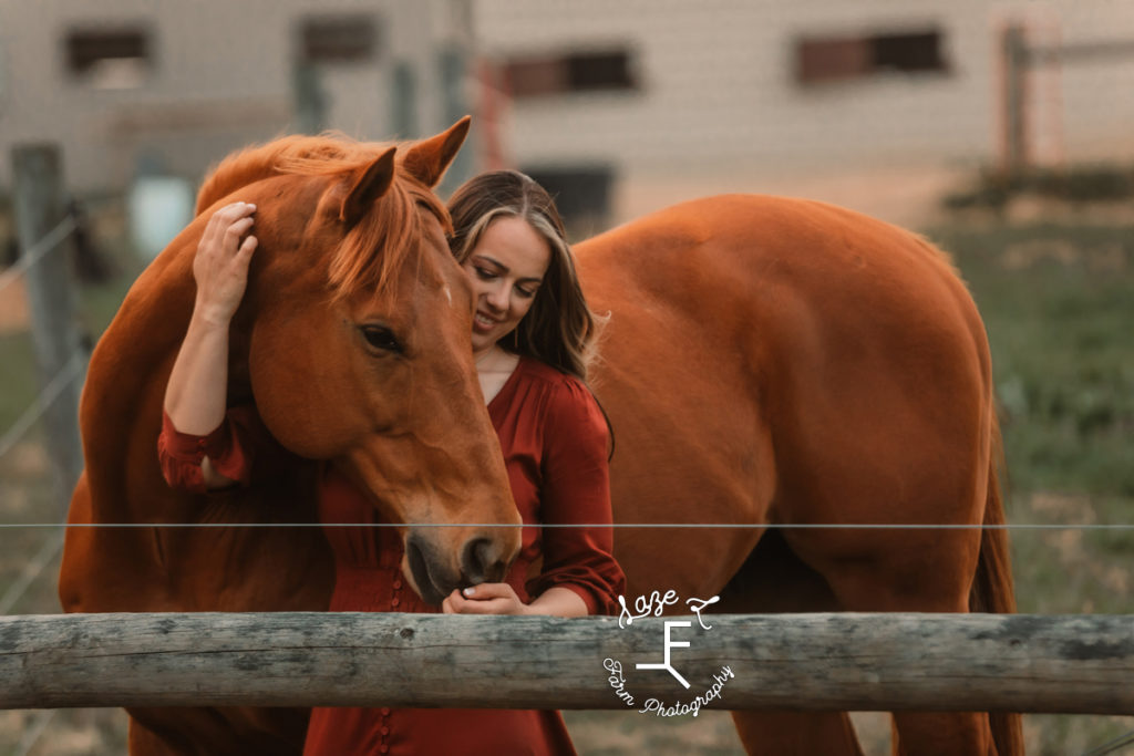 girl loving on horse behind a fence post