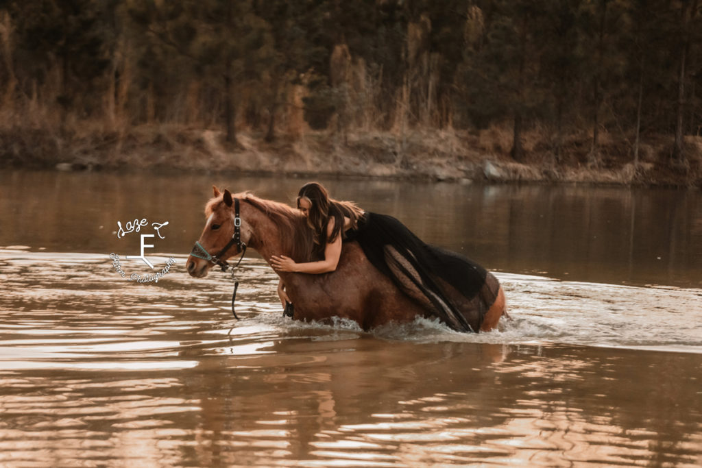 girl on horseback leaning forward to love horse in the water