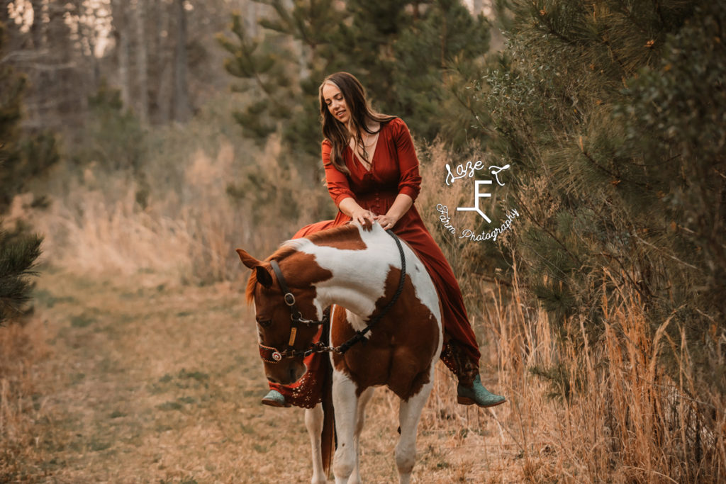 girl in long red dress riding paint horse