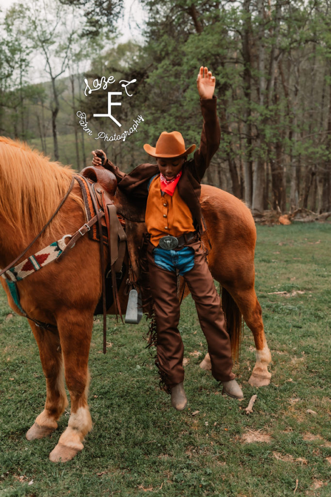 young cowboy jumping off horse