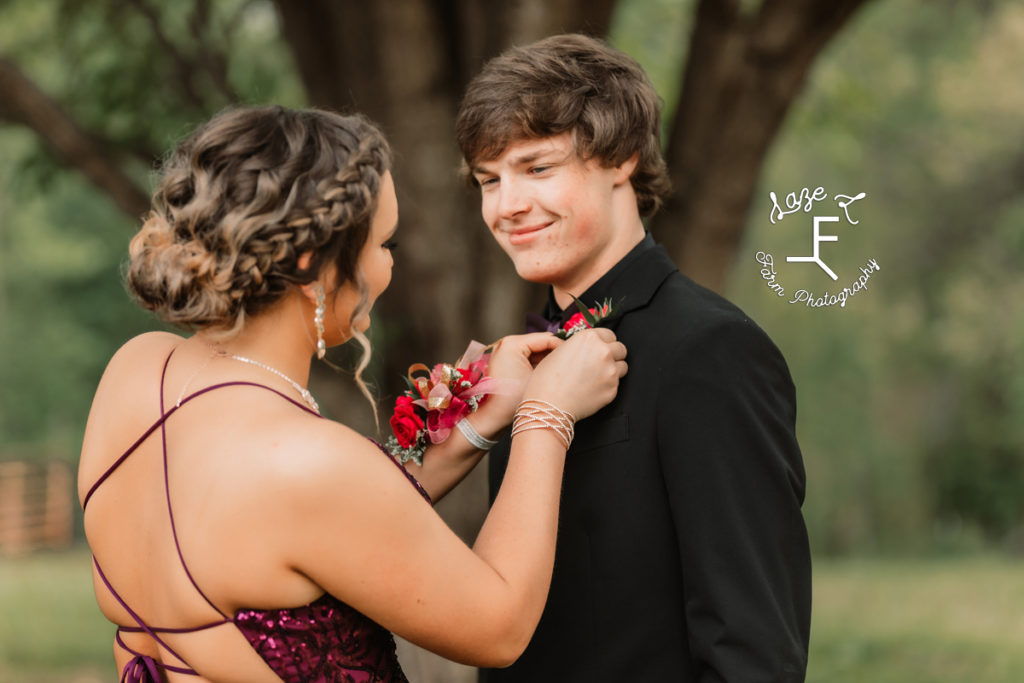 prom couple in purple as she is pinning boutonniere