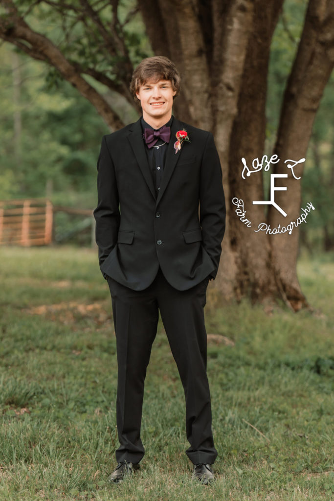 high school boy in black tux with purple bowtie