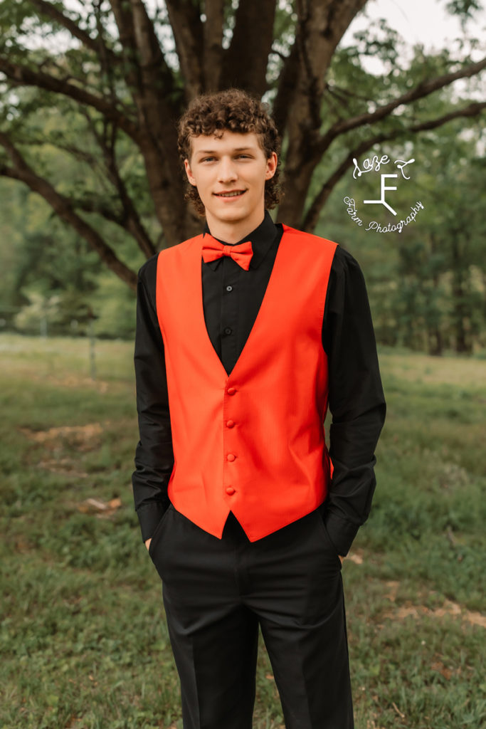 high school boy in orange vest and bowtie with black shirt