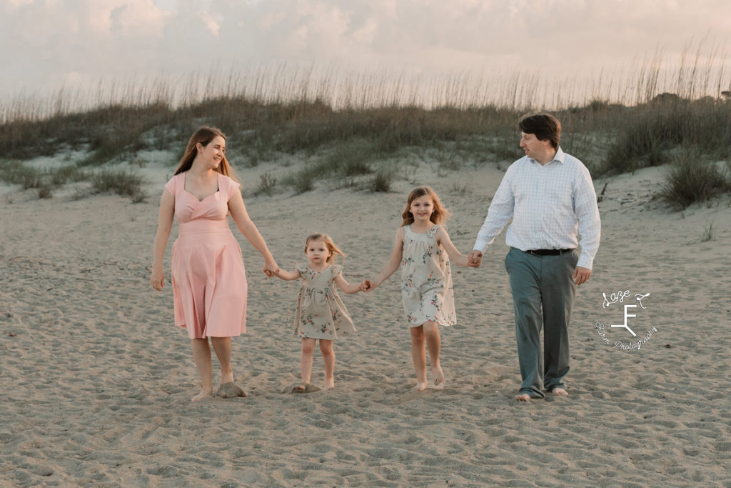 family with 2 girls walking on beach