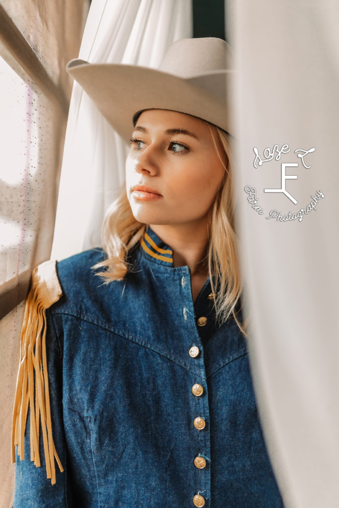 blonde cowgirl in vintage denim jacket looking out window