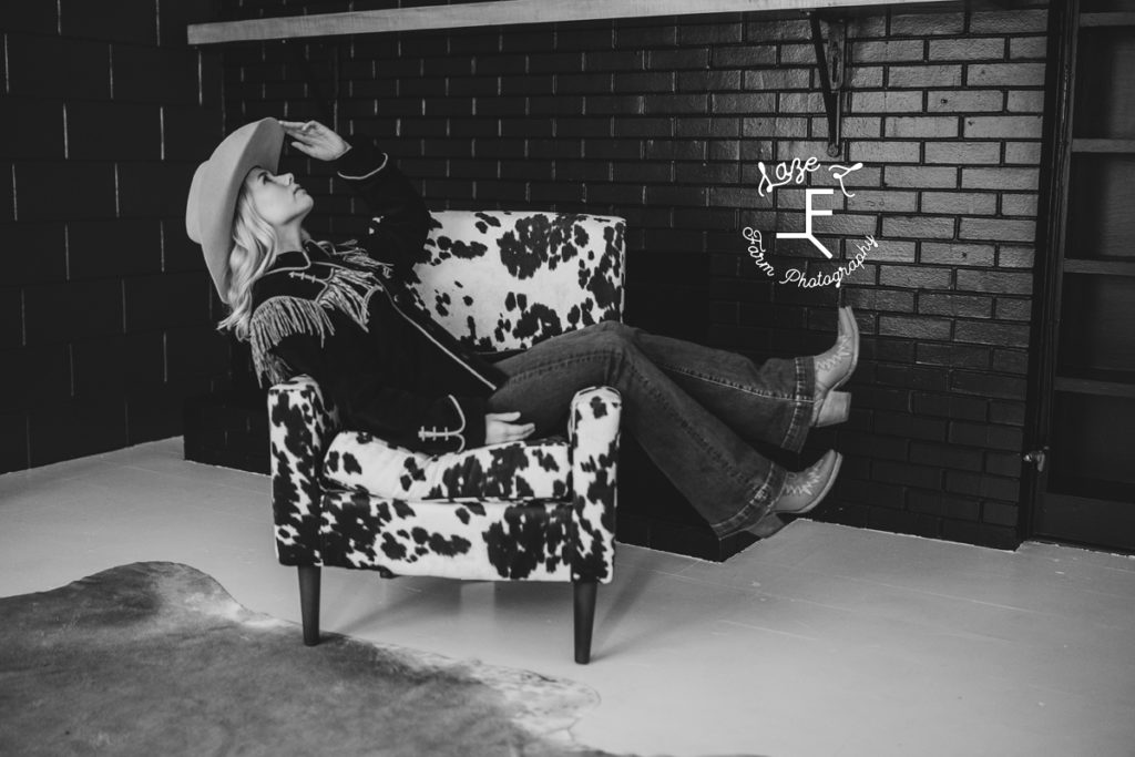cowgirl in cow print chair in black and white