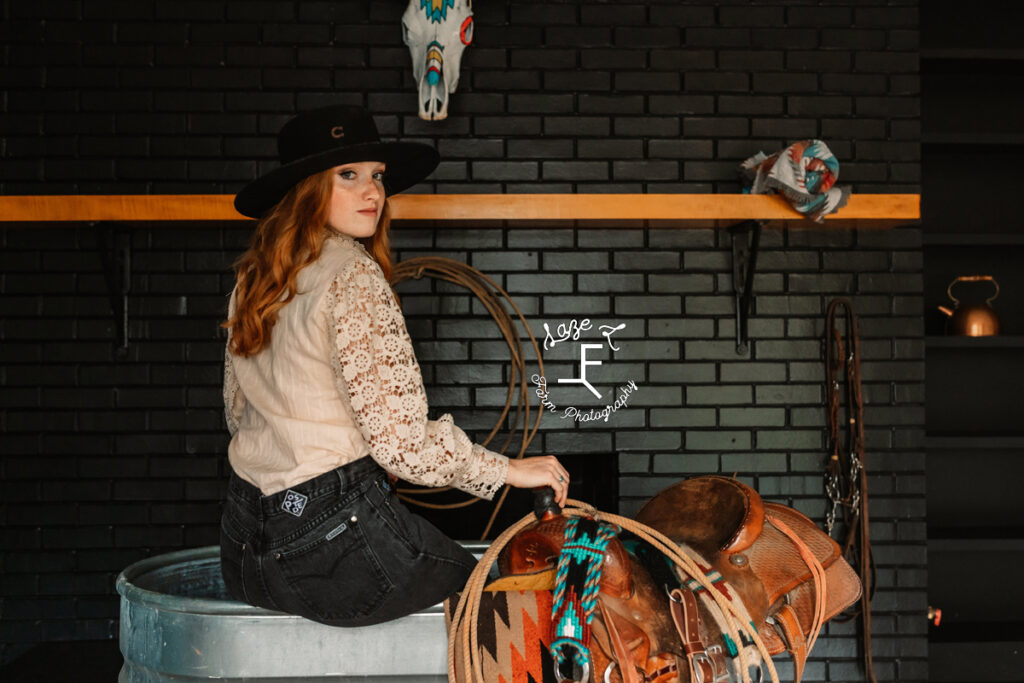 red head cowgirl sitting on water trough with back to camera