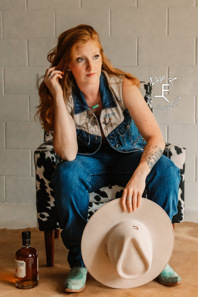 cowgirl in blue jean outfit in cow print chair