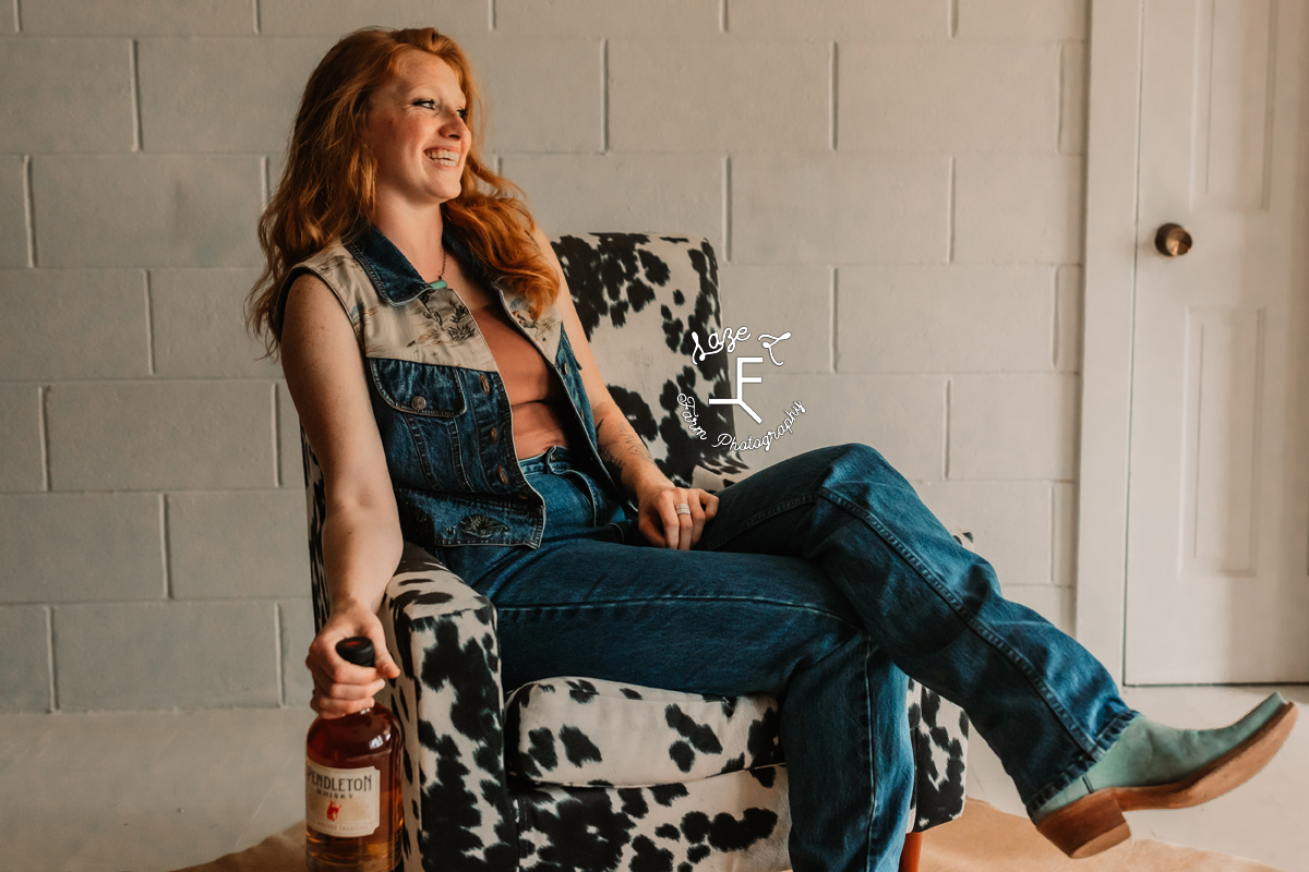 red head in cow print chair in blue jean outfit