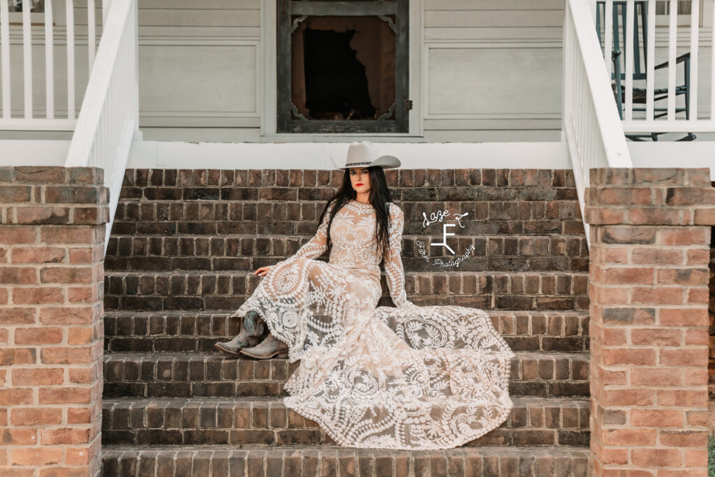 cowgirl in lace wedding dress sitting on brick steps