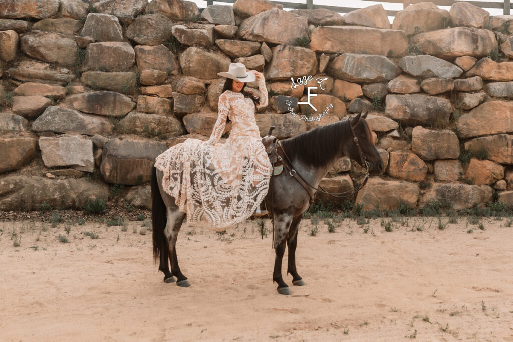 cowgirl sitting on horse with lace dress draped over his back