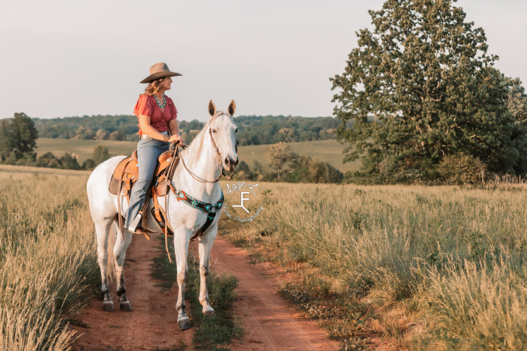 cowgirl on dirt road on gray horse