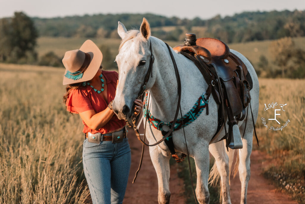 cowgirl on the ground beside her gray horse