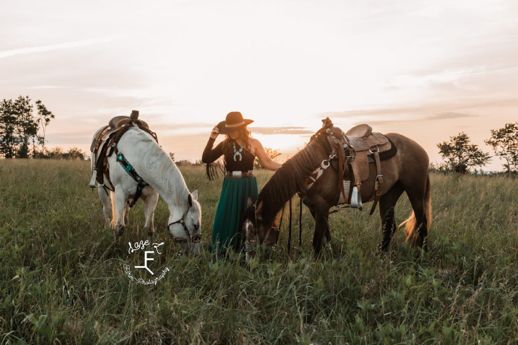 cowgirl with both horses and sun behind them