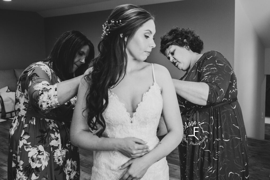 bride getting into dress with help in black and white