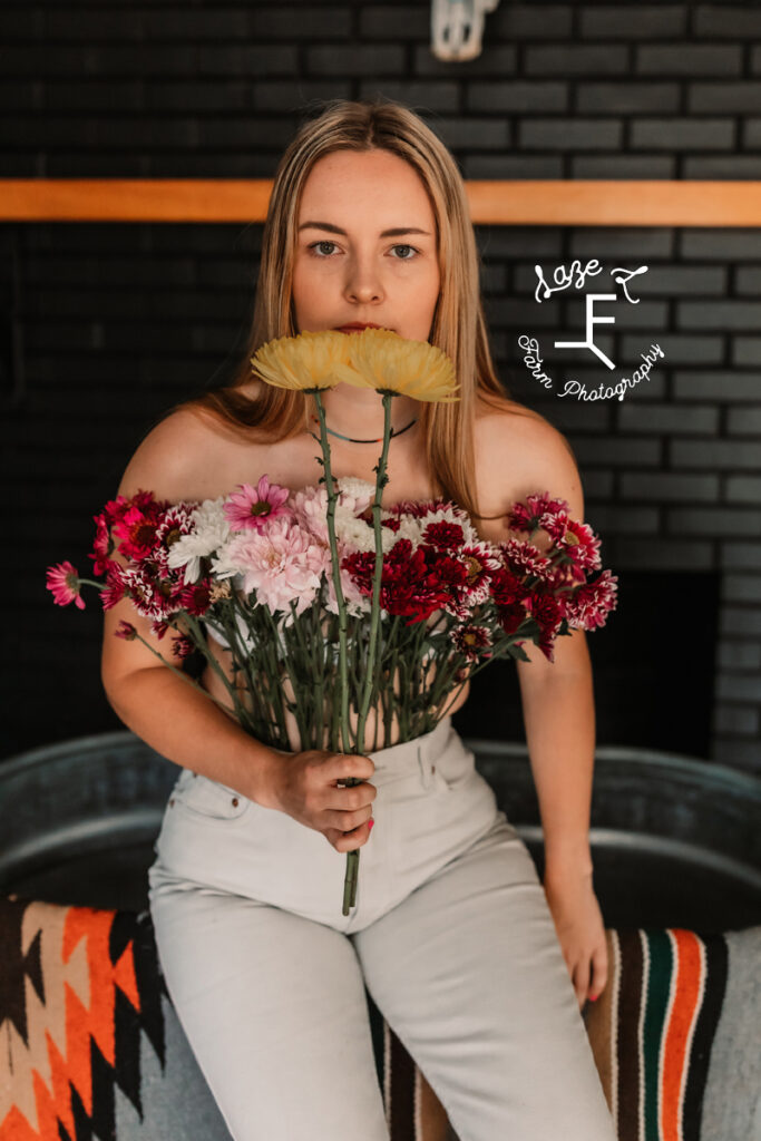 girl with flower pants holding yellow flowers up