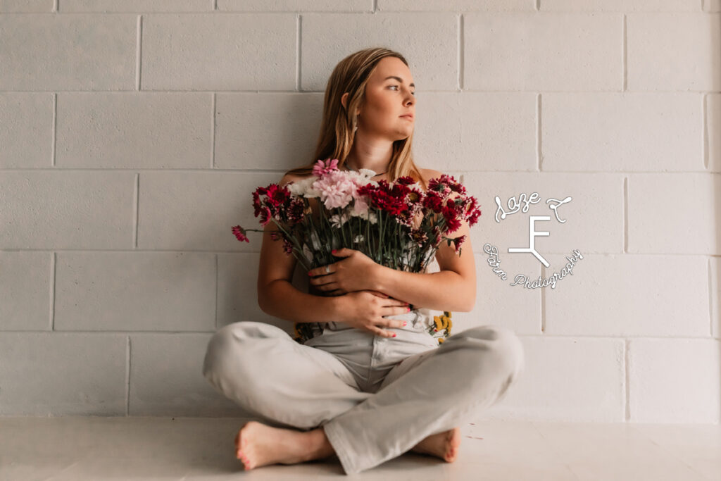 girl sitting in flower pants against wall