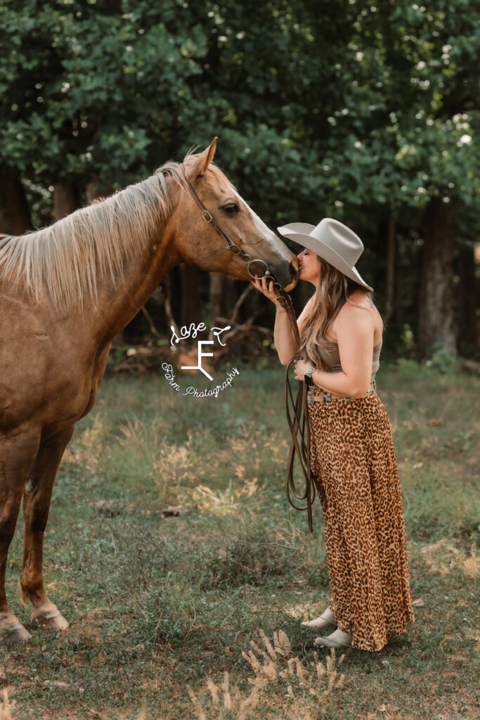 cowgirl kissing her mare on the nose