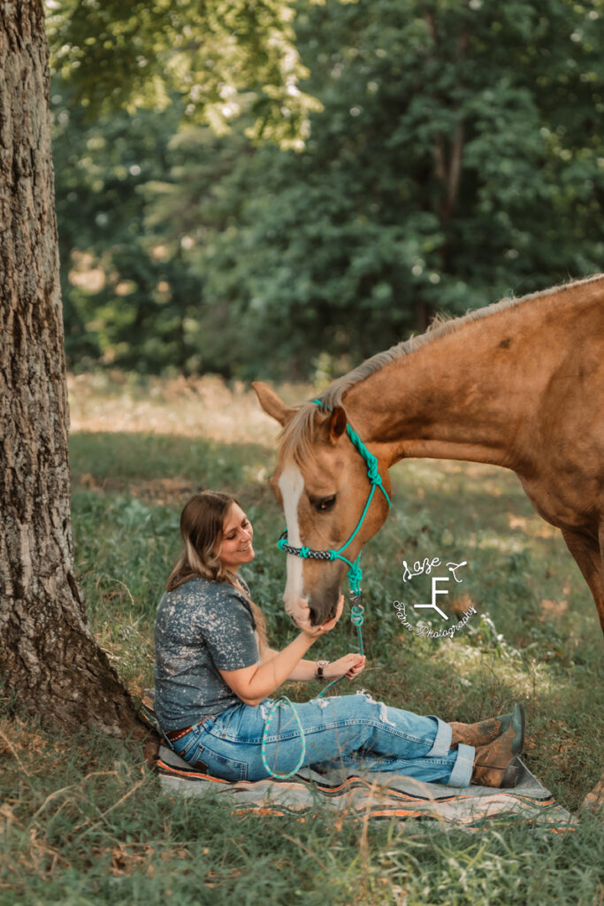 girl sitting by a tree with her mare