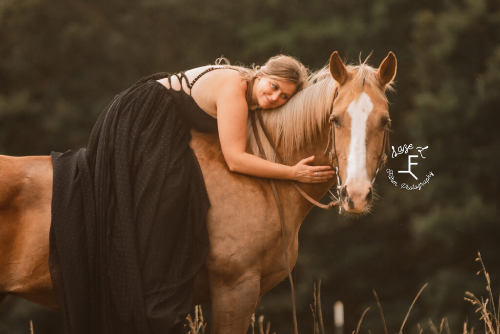 girl in black dress sitting on horse hugging her neck