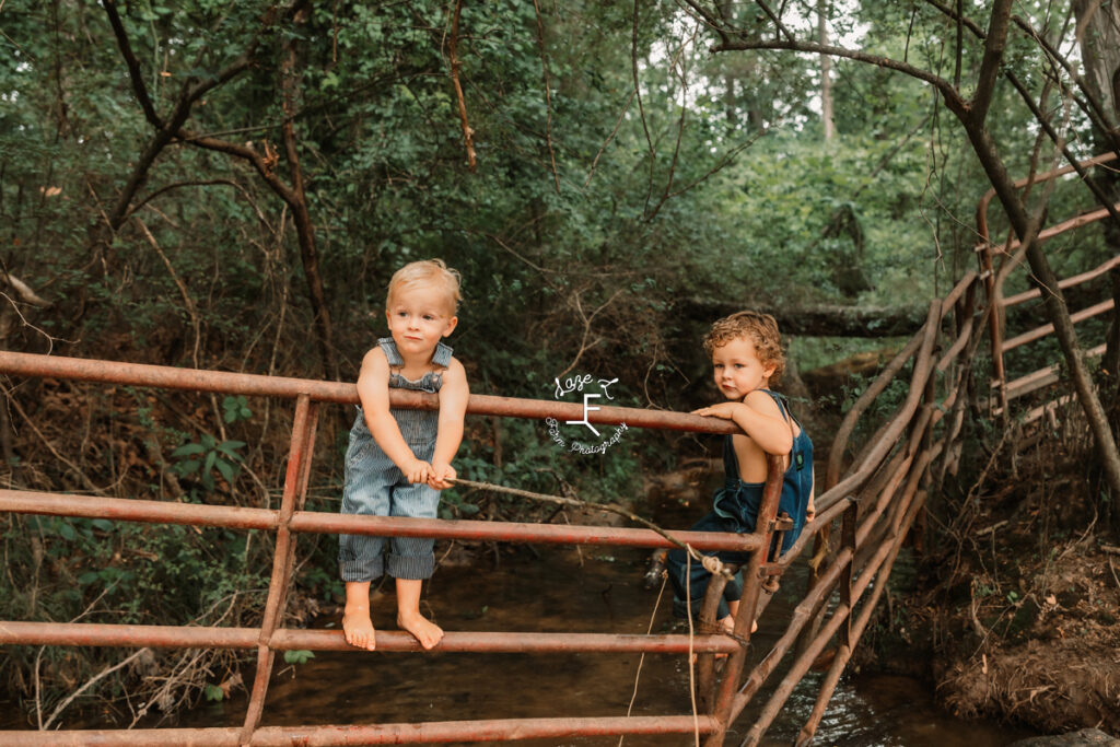 brothers sitting on gate panels over the creek fishing